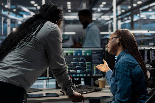People talking over a monitor showcasing a workflow